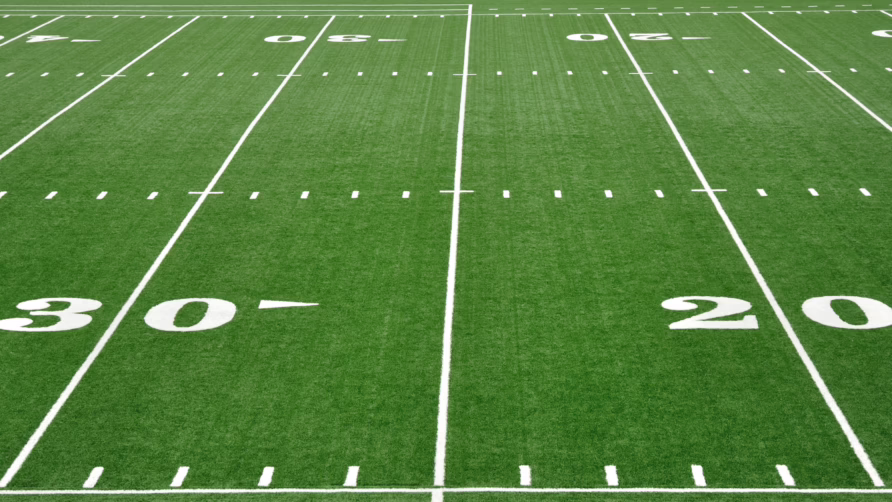 View of a football field showing yard lines and numbers marking distances on the green turf.